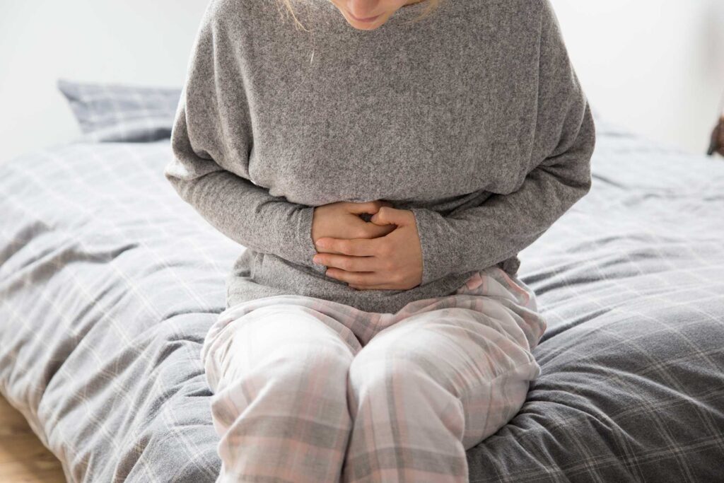 sick woman with hands on stomach suffering from intense pain