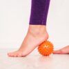 ginnastica-miofacciale-masterclass-pilates-cagliari un piede scalzo col tallone appoggiato su una pallina di gomma con piccole protuberanze usata per automassaggio